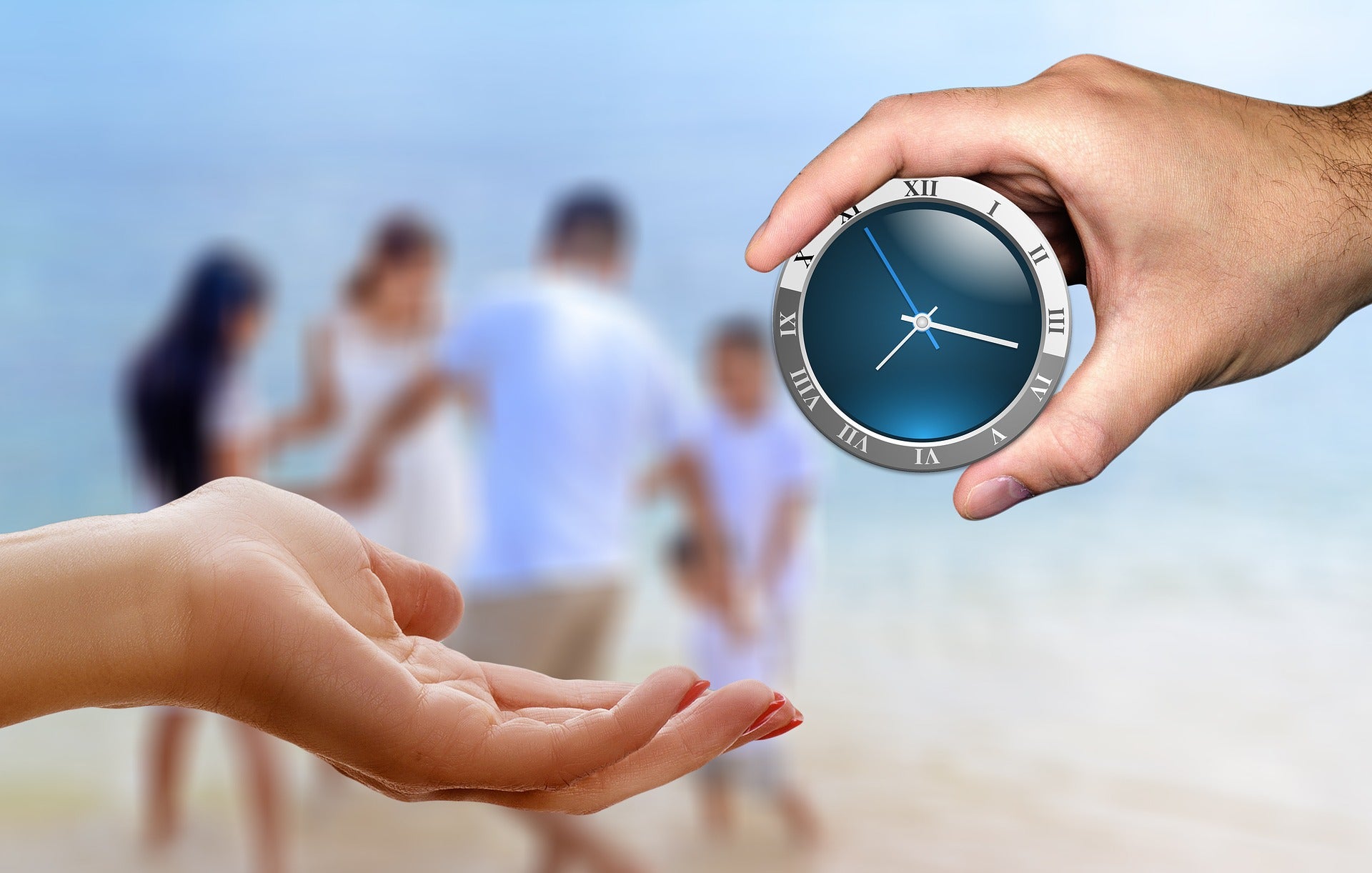 Zwei Hände im Vordergrund die einander eine Uhr reichen, im Hintergrund eine Familie am Strand